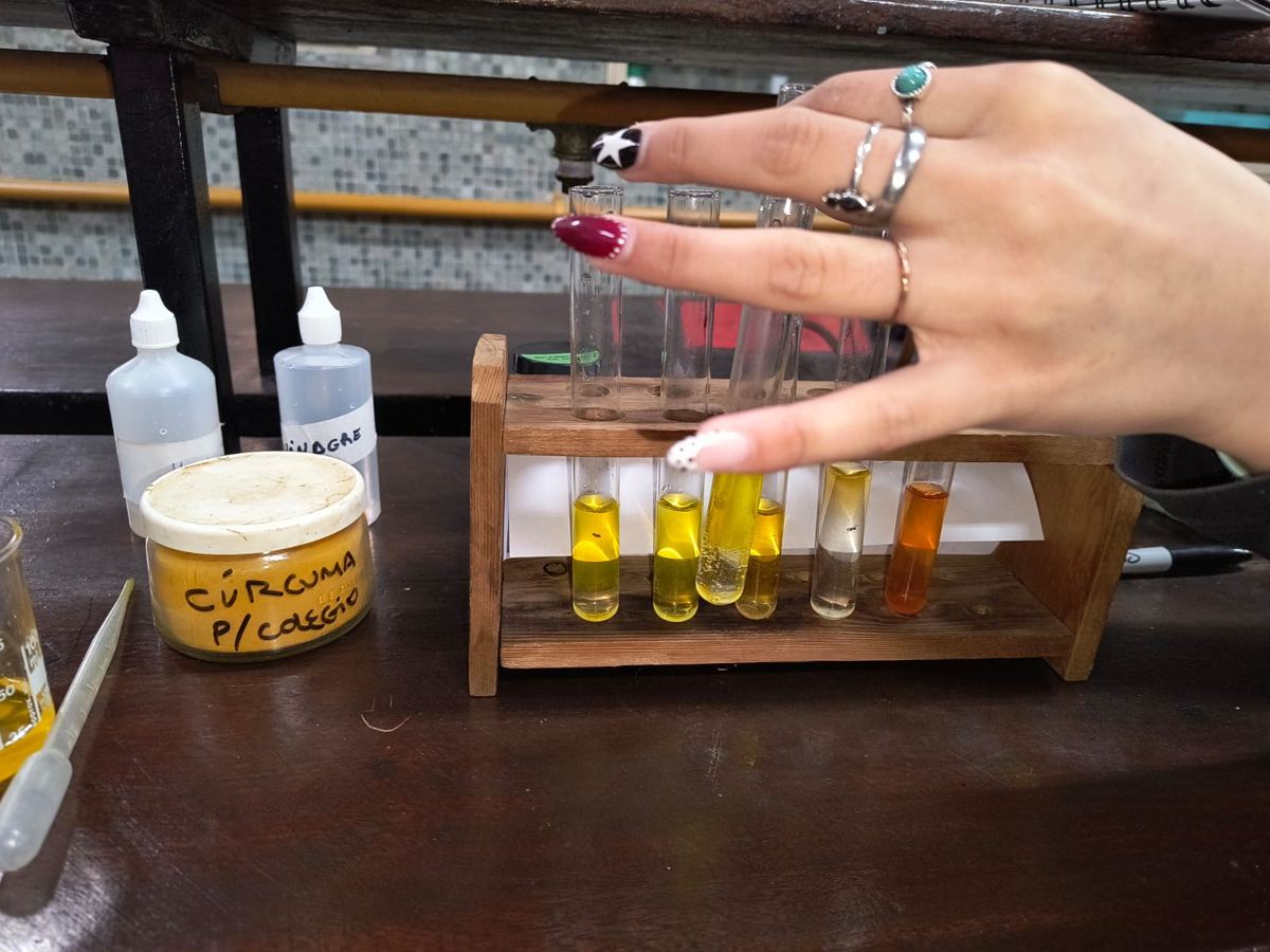Tubos de ensayo con cúrcuma y vinagre en una práctica de laboratorio.